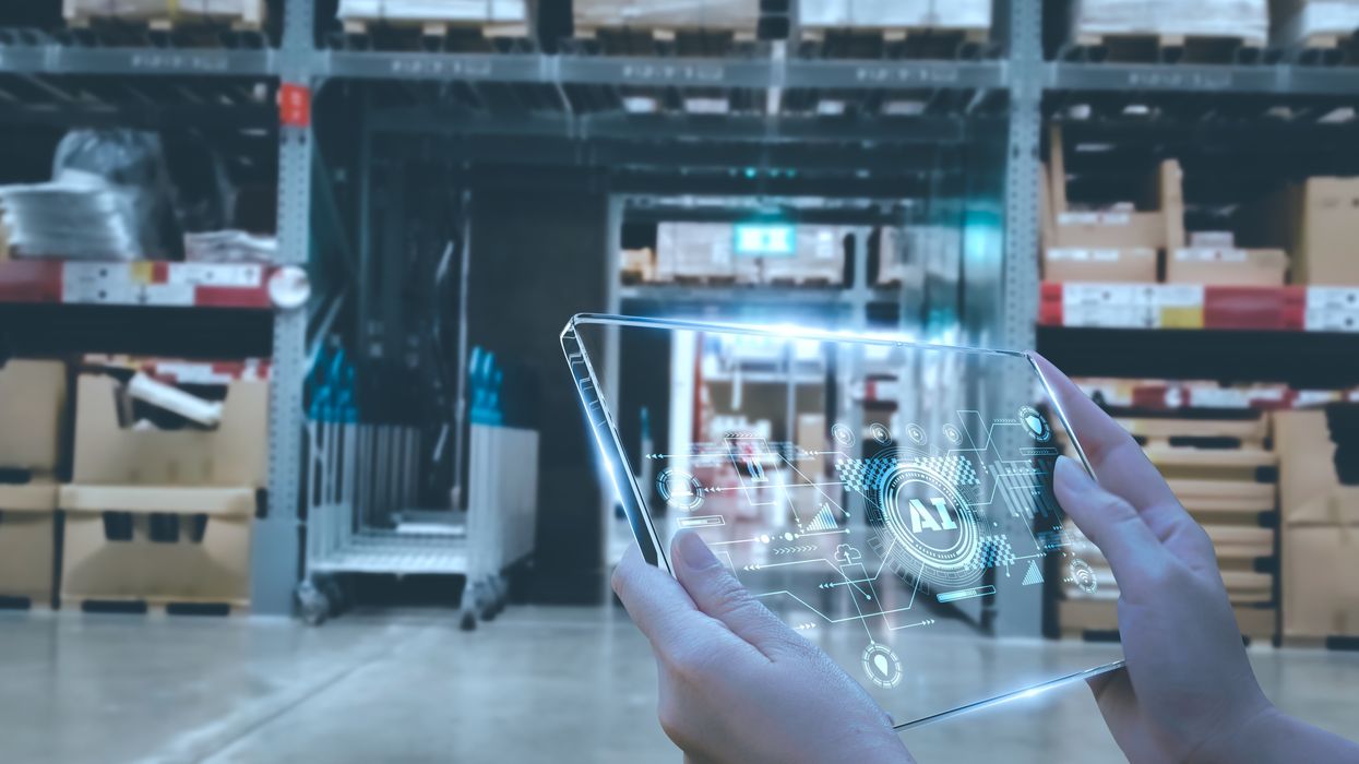 Woman's hands holding clear device with the letters "AI" on it in a warehouse