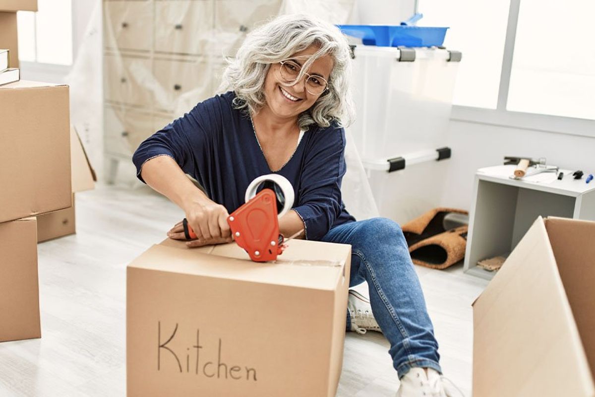Woman taping a box of kitchen supplies