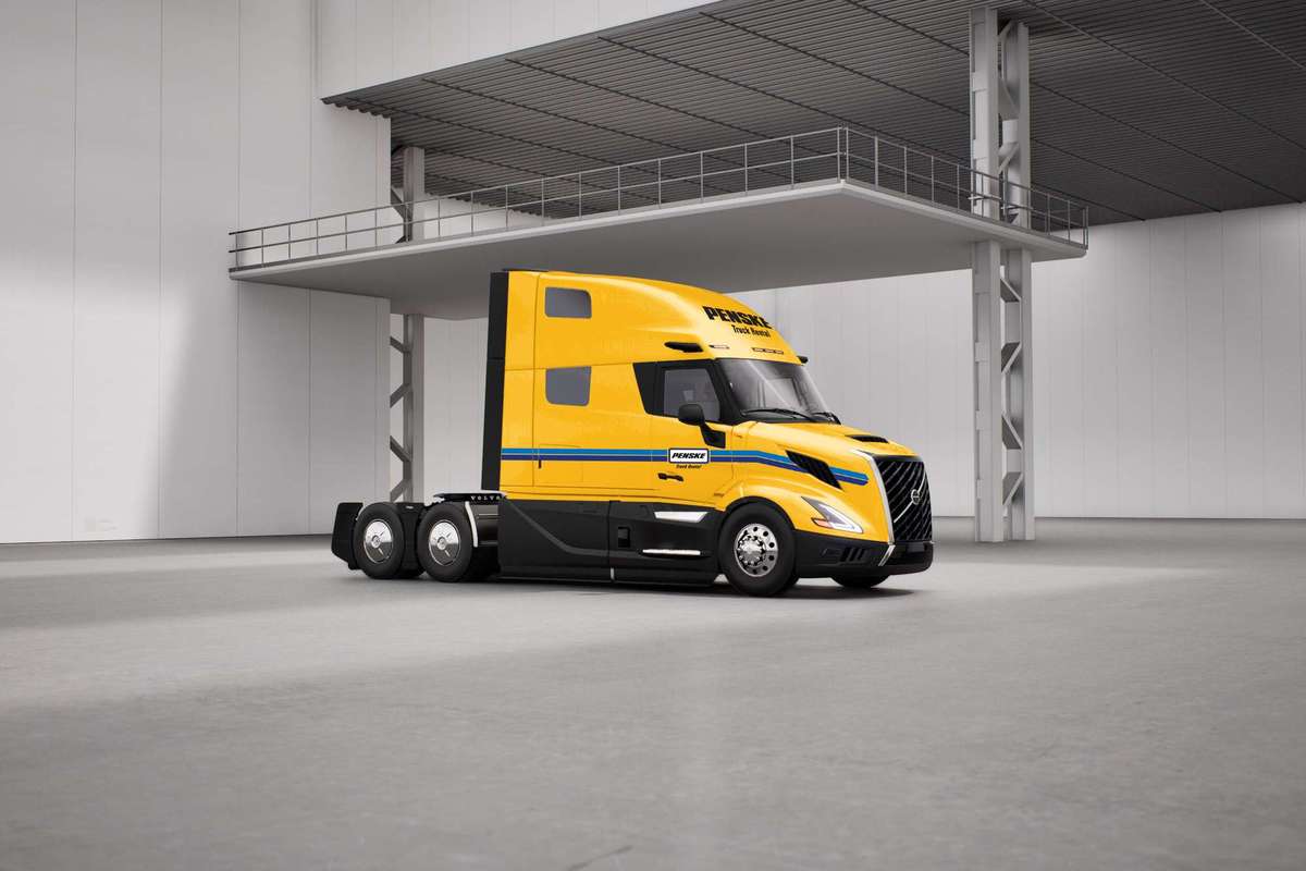 Yellow Penske semi-truck with no trailer sitting in a warehouse.