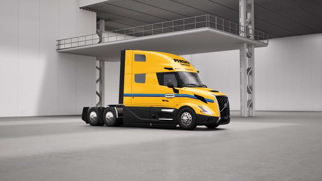 Yellow Penske semi-truck with no trailer sitting in a warehouse.